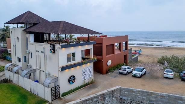 Ein Strandgebäude mit überdachter Terrasse, einem Pool und Blick auf den Ozean.