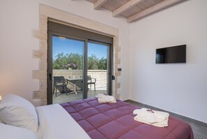 Une chambre à coucher avec un lit, une télévision et un balcon équipé d’une table et de chaises.