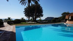 Ein Schwimmbecken mit klarem, blauem Wasser, umgeben von einer gepflasterten Terrasse und einem Zaun.