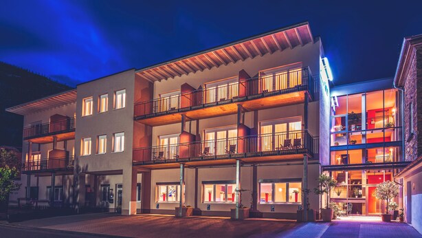 A multi-story hotel with balconies, large windows, and a well-lit facade. - Landhotel Sanct Peter (Bad Neuenahr-Ahrweiler)