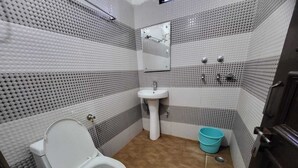 A bathroom with a toilet, sink, and mirror. - Hotel New Blue Sapphire Katra (Reasi)