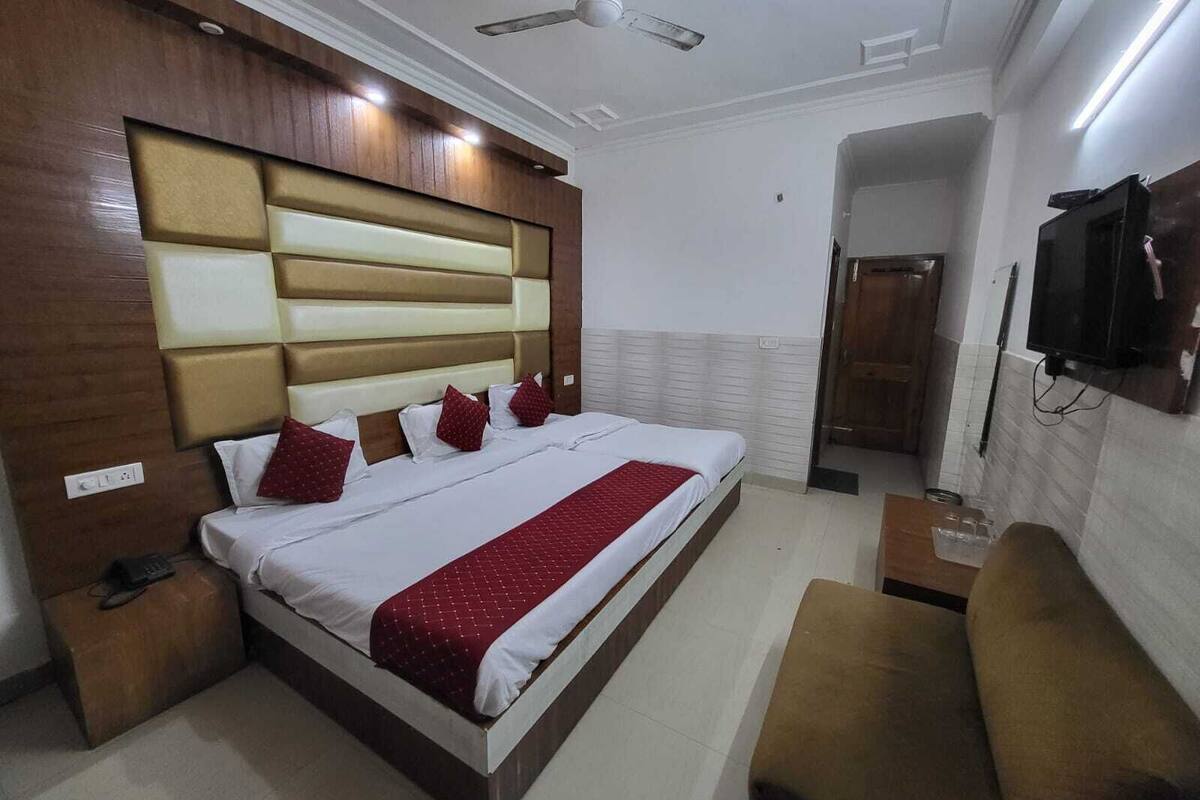 A hotel room with a large bed, a bedside table, a TV mounted on the wall, and a ceiling fan.