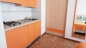 A compact kitchen with orange cabinets, a sink, and a gas stove. - Residence Rex (Chioggia)