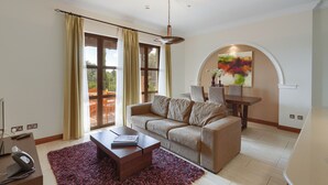 A living room with a sofa, coffee table, and a painting on the wall. - Aphrodite Hills Rentals - 1 Bedroom Apartment - AHA12 (paphos)