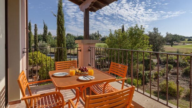 A balcony with a table set for two, featuring a plate, cutlery, and a bowl of fruit and juice. - Aphrodite Hills Rentals - 1 Bedroom Apartment - AHA12 (paphos)