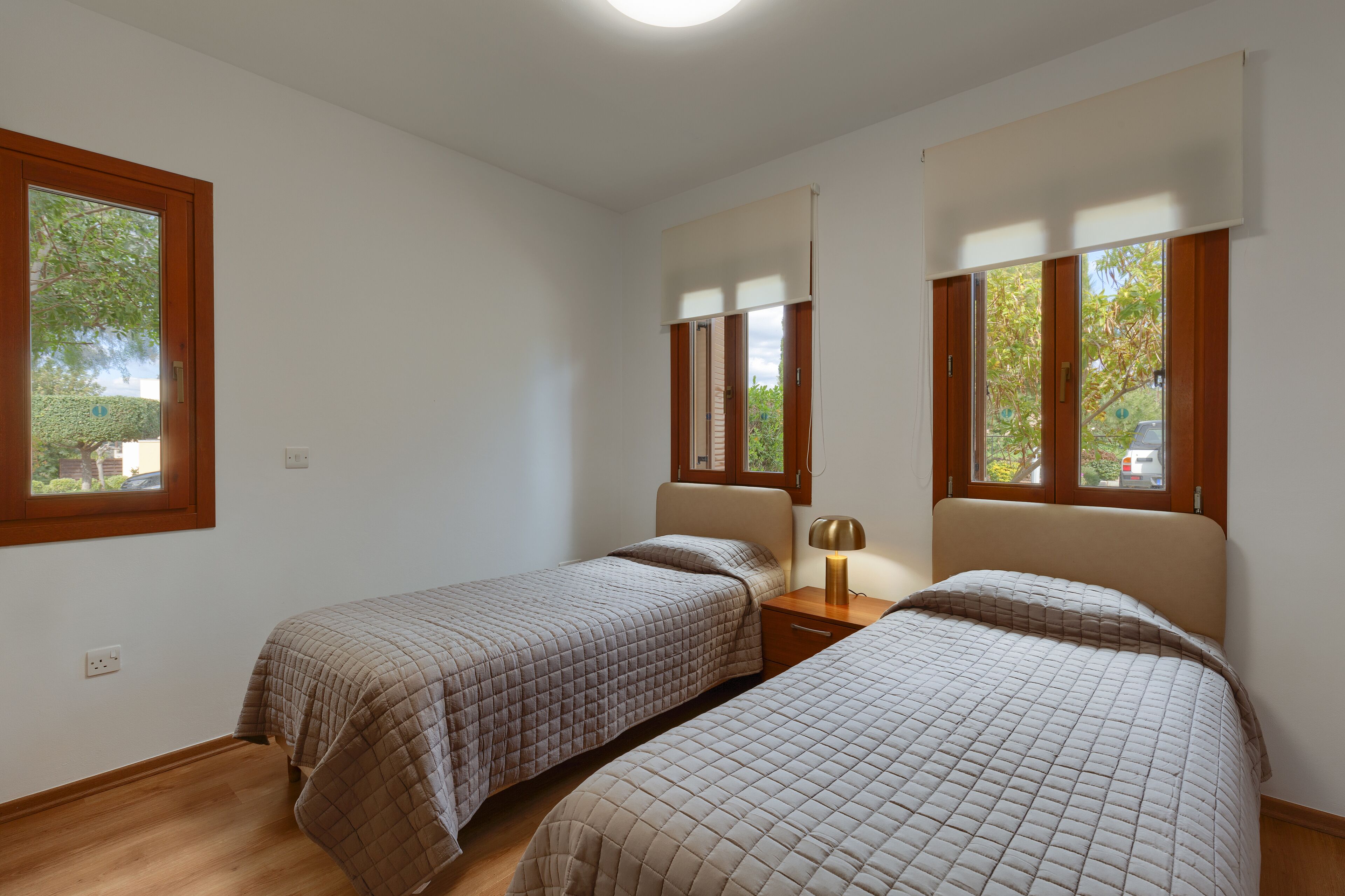 A bedroom with two beds, a nightstand, and a window.