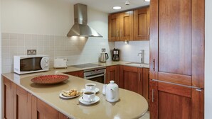 A modern kitchen with wooden cabinets, a microwave, a toaster, and a coffee maker. - 2 Bedroom Apartment - AHI02 (paphos)