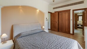 A bedroom with a bed, nightstand, lamp, wooden wardrobe, and a mirror. - 2 Bedroom Apartment - AHI02 (paphos)