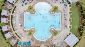 An aerial view of a resort with a central swimming pool surrounded by lounge areas and palm trees. - Emerald Gem by AvantStay | Pool Access, 3mins to Beach! (Watersound)