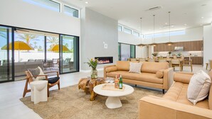 A spacious living area with a large sofa, a coffee table, and a fireplace. - Polo Villas Bella | 2 Homes | Putting Green, Bocce Ball |  Sleeps 32 (La Quinta)