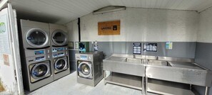 A public laundromat with multiple washing machines and a large sink area.
