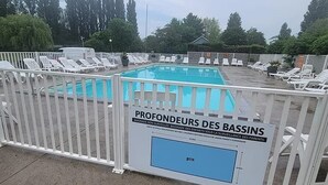 Un espace autour d’une piscine, délimité par une clôture blanche, et sur lequel est apposée une pancarte indiquant qu’il est réservé à l’usage des sauveteurs.