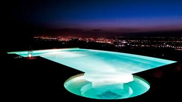 Vista notturna di una piscina con sullo sfondo un panorama urbano.