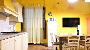 La cuisine est équipée d’un évier, d’une cuisinière et d’un four à micro-ondes. On y trouve une table à manger avec des chaises, et un téléviseur fixé au mur.
