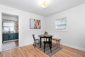 A modern kitchen with teal cabinets, a black dining table, and a colorful abstract painting.