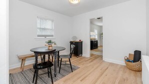 A dining area with a round table, two chairs, a bench, a potted plant, and a small cabinet. - White Clay Creek Cottage (Newark)