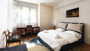 Een slaapkamer met een bed, een bureau, een stoel en een kledingkast.