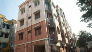A multi-story building with a pink facade, multiple balconies, and a visible entrance. - Izi Apollo Stay (Chennai)