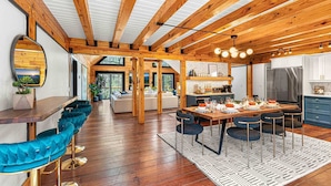 A spacious kitchen with a dining area, wooden beams, and a large window.