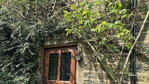 Un bâtiment en pierre avec une porte en bois et une petite fenêtre.