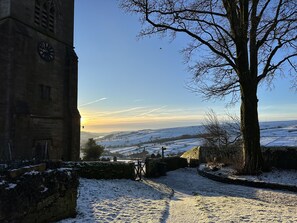 Schneebedeckte Landschaft mit einem historischen Gebäude und einem großen Baum.