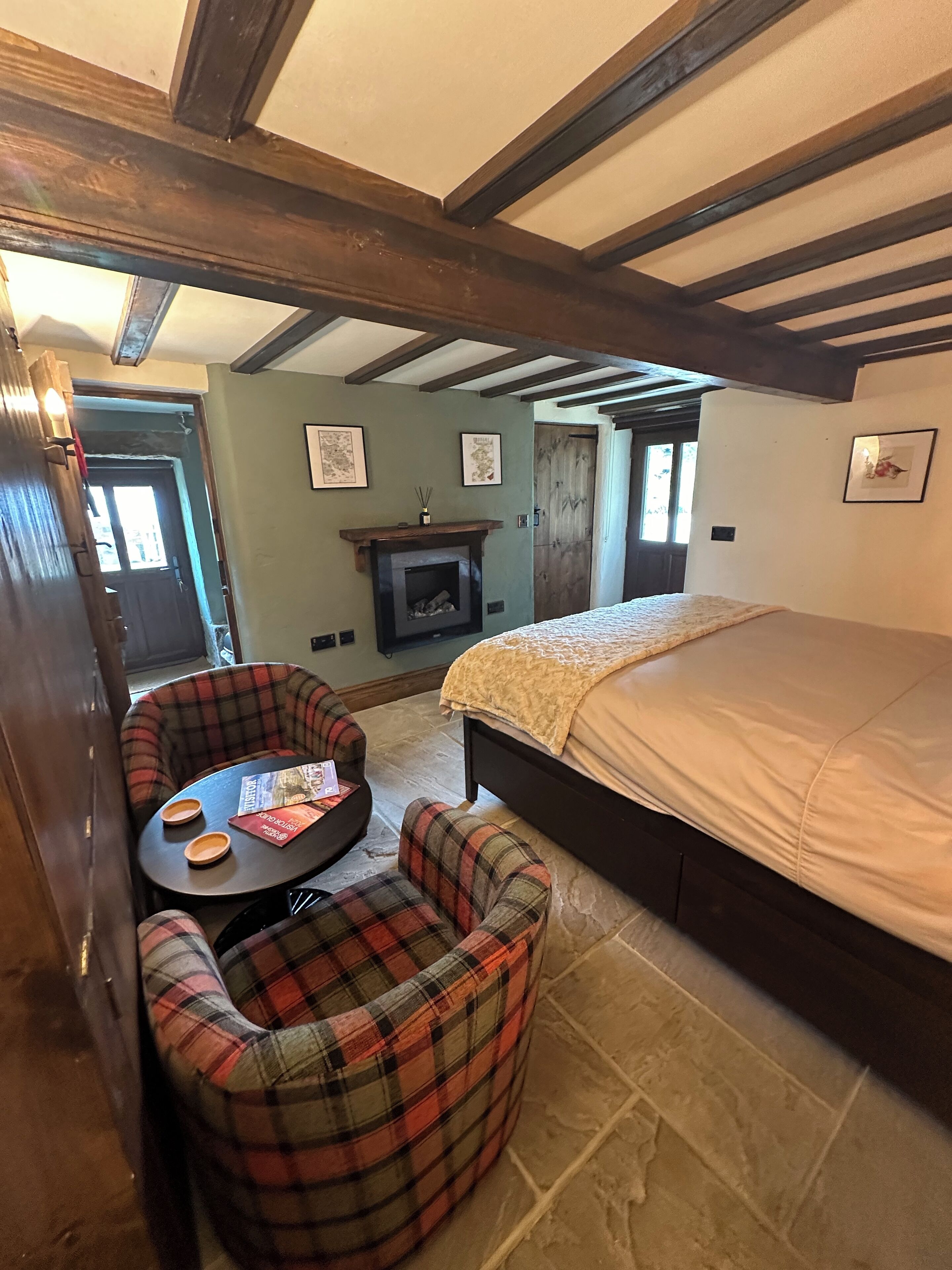 A cozy room with a bed, a fireplace, and a small table with chairs.