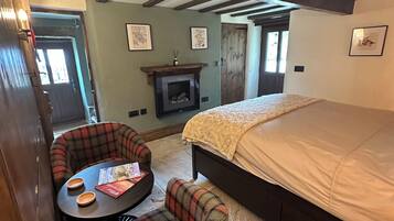A cozy room with a bed, a fireplace, and a small table with chairs.