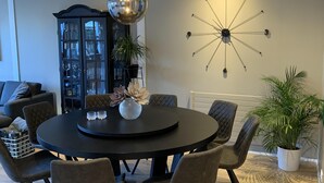 Un comedor moderno con una mesa redonda, sillas oscuras y una lámpara colgante en el centro.