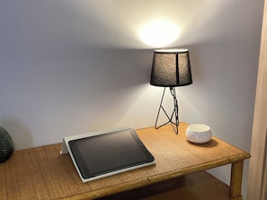 A tablet on a wooden table with a lamp and a white mug beside it.