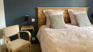 A bedroom with a bed, two pillows, a nightstand, a lamp, and a chair.