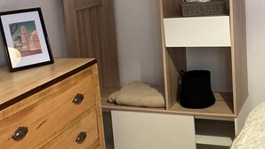 A bedroom with a wooden wardrobe, a bedside table, and a bed.