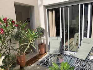 A balcony with two chairs, a glass table, and potted plants.