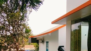 Un sendero que lleva a un edificio con fachada blanca y detalles en naranja.