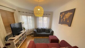A living room with a TV, sofa, and a red couch. - Cosy 3-bed Apartment in Hythe High Street (Hythe)