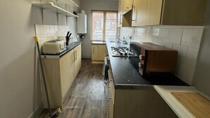 A compact kitchen with wooden cabinets, a gas stove, and a countertop. - Cosy 3-bed Apartment in Hythe High Street (Hythe)