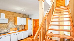 A kitchen with wooden cabinets, a white refrigerator, and a wooden staircase leading to an upper level. - 2 bedroom lovely apartment in Mirow (Mirow)