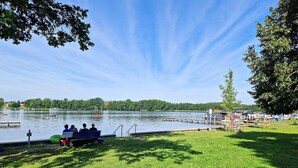 A lakeside park with a grassy area, a dock, and a boat. - 2 bedroom lovely apartment in Mirow (Mirow)
