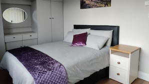 A bedroom with a bed, a bedside table, a wardrobe, a mirror, and a painting on the wall. - Gateway to Killarney (Killarney)