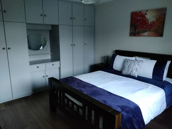 A bedroom with a bed, a wardrobe, a mirror, and a painting on the wall. - Gateway to Killarney (Killarney)