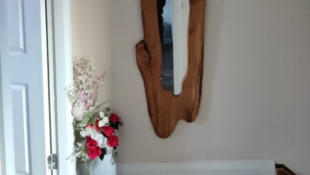 A wooden wall art piece with a unique shape, a white door, and a vase with flowers on the floor. - Gateway to Killarney (Killarney)