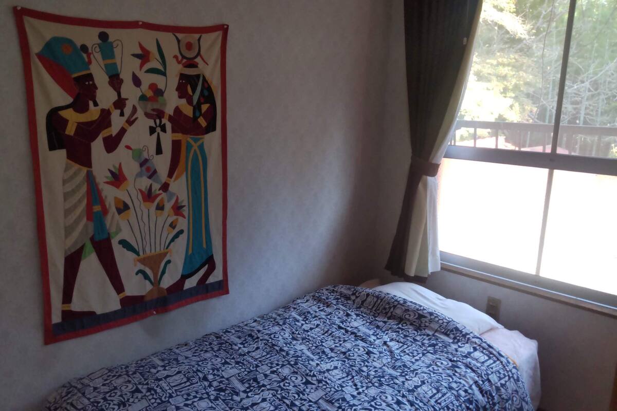 Um quarto com cama, um objeto decorativo na parede e janela com cortinas.