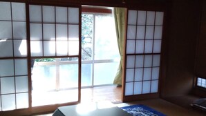 A traditional Japanese room with tatami flooring, shoji screens, and a futon bed. - Guesthouse Oomiya base (Chiba)