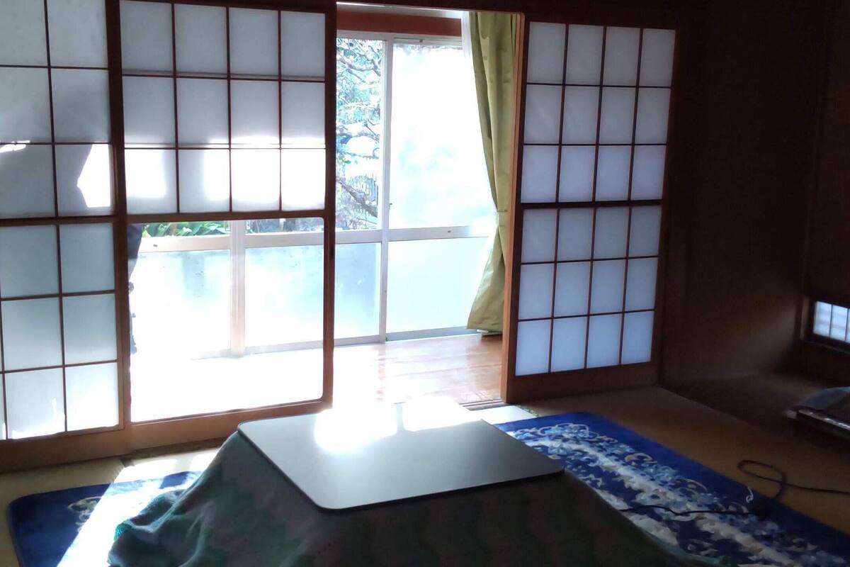 Um quarto japonês tradicional com piso de tatame, biombos shoji e futon.
