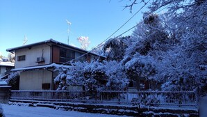 A residential area with houses, a fence, and snow-covered trees. - Guesthouse Oomiya base (Chiba)