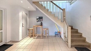 A staircase leading to a landing with a small table and stools, a wall-mounted bulletin board, and sports equipment. - Ferienwohnung Hohen Wangelin (Hohen Wangelin)