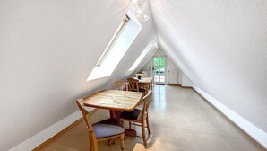 A high-ceilinged room with a sloped ceiling and skylights, wooden furniture, and a door leading outside. - Ferienwohnung Hohen Wangelin (Hohen Wangelin)