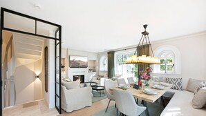 Un salon moderne comprenant un coin repas, un escalier et une grande fenêtre avec des rideaux.