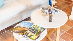 A small round table with a magazine and a decorative vase on it, placed on a tiled floor. - Gemütlich. Ruhig. Garten (Sylt)