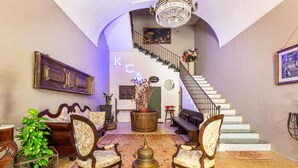 Un vestíbulo imponente con una escalera, muebles antiguos y un candelabro.