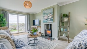 Una sala de estar acogedora con chimenea, televisor y vistas al exterior.